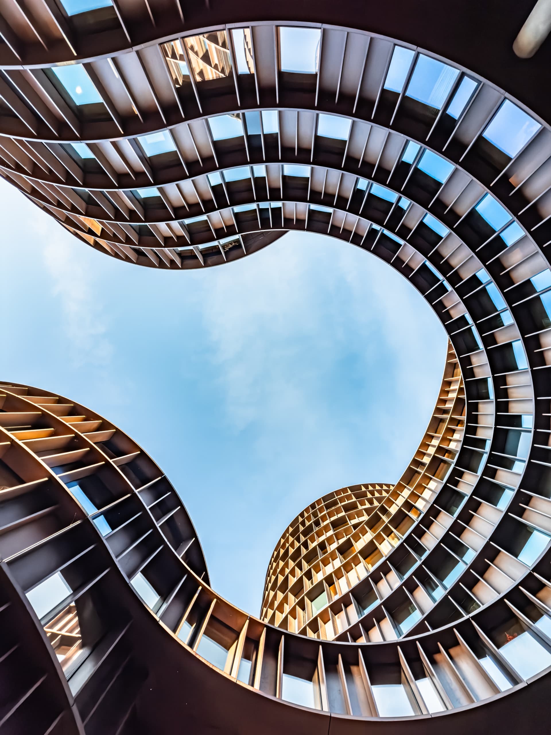 Low-angle view of a modern glass-and-concrete office building facade against a blue sky